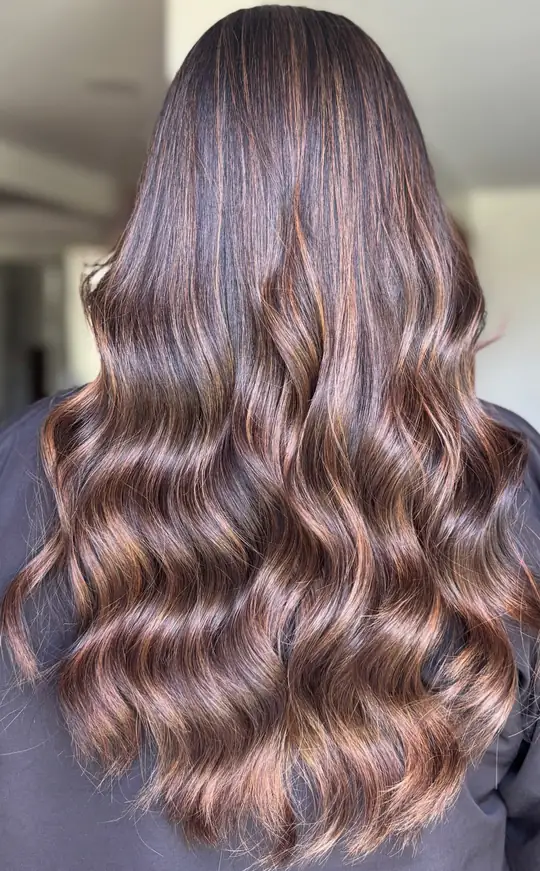 Resultado de color número 1: castaño con mechas cobrizas en ondas, visto de espaldas en el salón